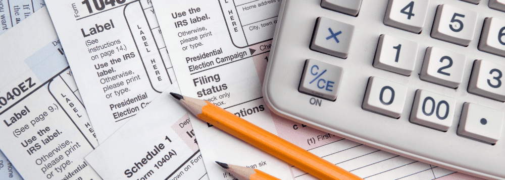 A picture of a calculator and some tax forms.