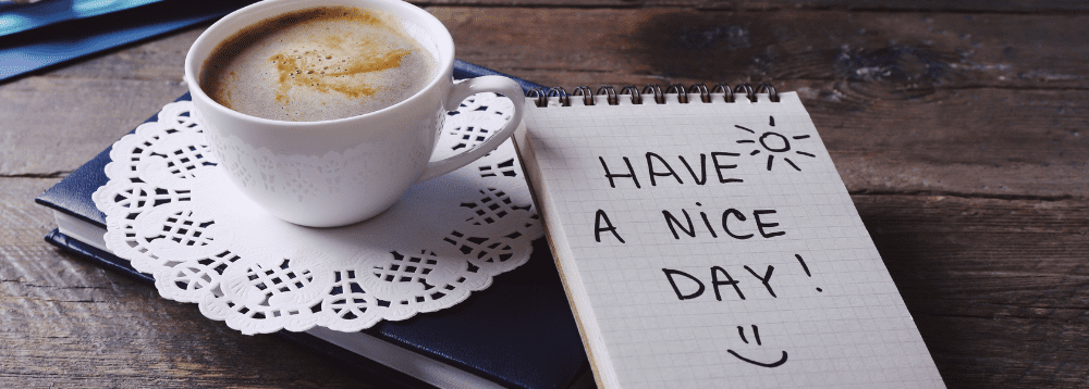 A cup of coffee and a ntoe that says 'have a nice day'.