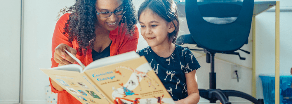 A child and her caregiver reading together.