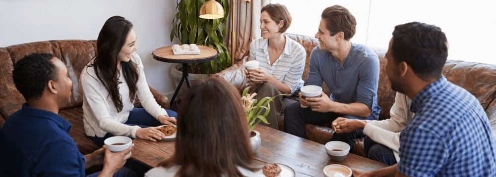 A group of people sharing coffee and tea, and talking.