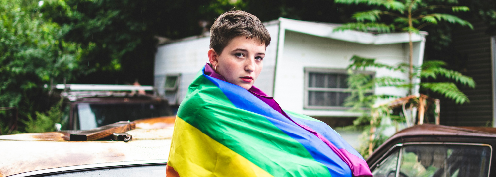 A young person wearing a Pride Flag.