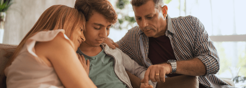 Two foster carers supporting and embracing their young person.