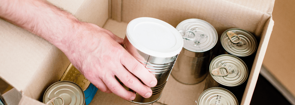 A person retrieves tinned food from a food parcel.