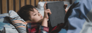 Picture: a child using an iPad in bed.