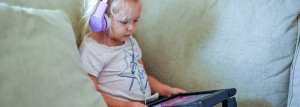 A young child using an ipad with headphones. 