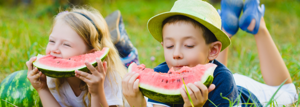 Two children eating a watermelon to encourage healthy eating habits in foster children.